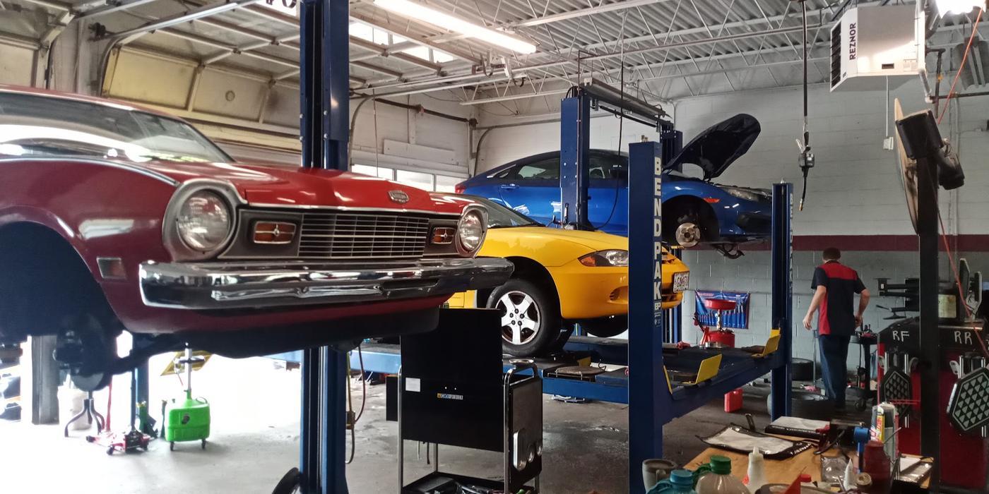 The shop floor with a vintage compact and two modern cars raised on lifts